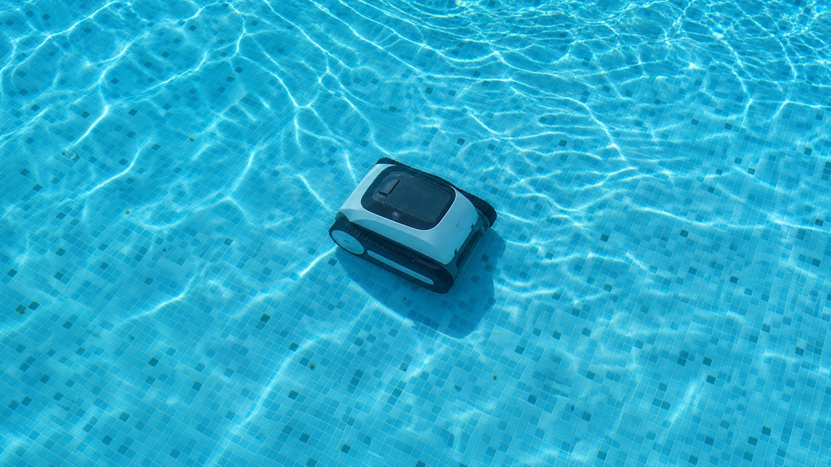 Robô limpa-fundos sem fios a trabalhar a meio do ciclo numa piscina residencial cristalina